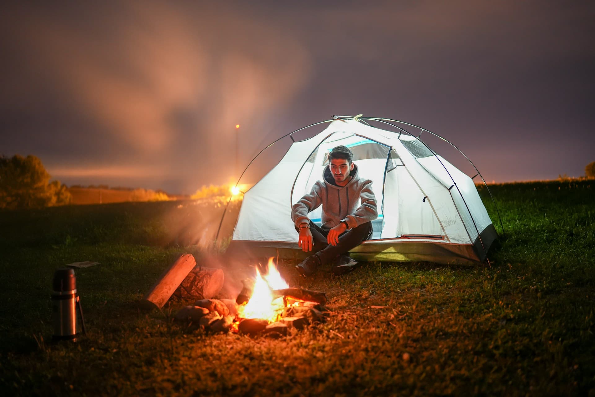 a man sitting in front of a campfire at night