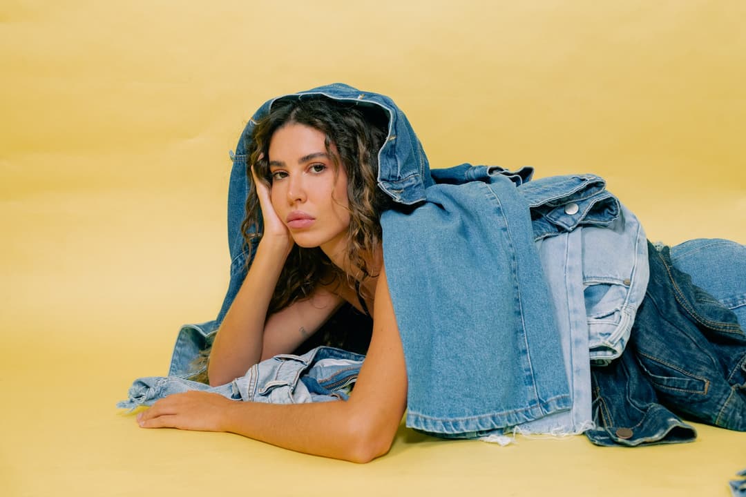 a woman laying on the ground with a jean jacket over her head